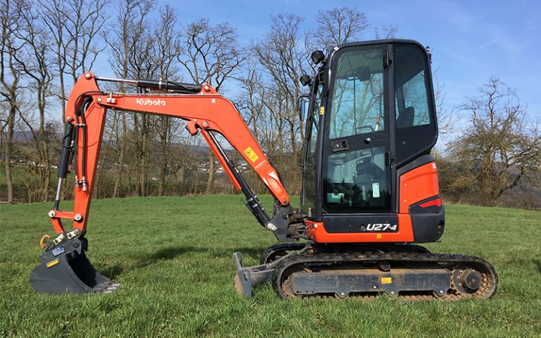 Minibagger Kubota U27-4 steht auf der Wiese und hat die Schaufel unten